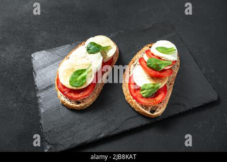 Bruschetta caprese classica italiana con mozzarella e pomodori. Foto Stock