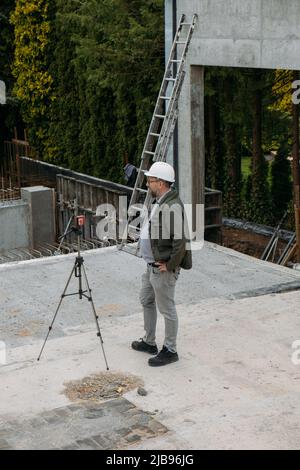 Opere geodetiche. Ingegnere Surveyor che utilizza attrezzature geodetiche in cantiere. Attrezzatura professionale per building. Lavoro come un topografo. Ottico Foto Stock