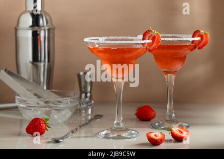 Cocktail margarita alla fragola fatti in casa con strumenti da bar sul tavolo. Preparazione di cocktail rinfrescanti estivi. Foto Stock