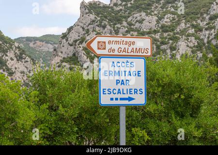 Un segno per l'eremo di Saint-Antoine de Galamus troglodita è stato tagliato fuori dalla roccia nel 7th secolo, sul lato della gola. Foto Stock