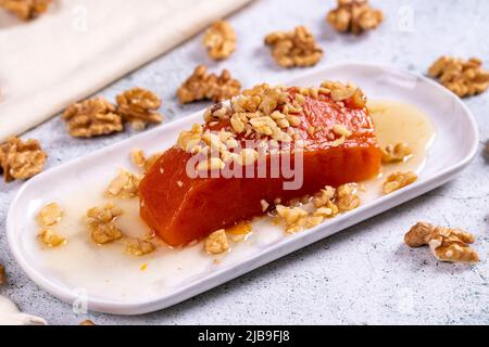 Dessert di zucca. Prelibatezze della cucina tradizionale turca. Dessert di zucca con noci su sfondo di pietra. Primo piano. Nome locale kabak tatlisi Foto Stock