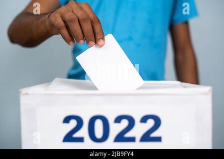 L'uomo che mette la carta delle urne in 2022 scrutinio - concetto di elezione 2022, voto e democrazia Foto Stock