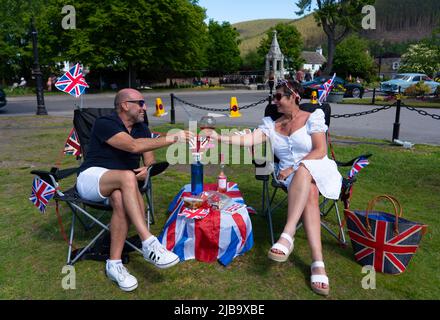 Ballater, Scozia, Regno Unito. 4 giugno 2022. La celebrazione del Giubileo del platino della Regina si celebra nel villaggio di Ballater, vicino a Balmoral, sul Royal Deeside, nell'Aberdeenshire. PIC; Julie e George dall'Hampshire godono di bevande sul prato nel verde del villaggio a Ballater. George era una guardia reale nella vicina Balmoral 40 anni fa. Iain Masterton/Alamy Live News Foto Stock