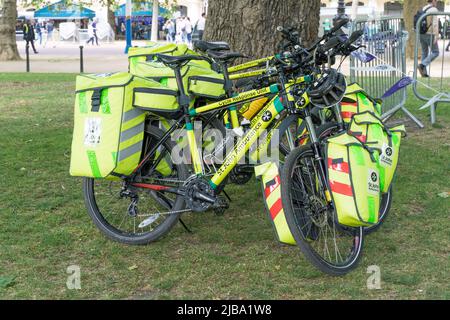 Le biciclette dell'unità di risposta del ciclo di St John Ambulance si prestano contro un albero. Foto Stock