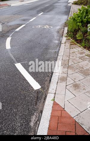 Segnaletica su una strada asfaltata che permette di andare in bicicletta. Pista ciclabile con simboli e linea tratteggiata. Concetto di movimento sicuro. Foto Stock