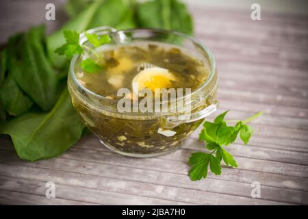 Zuppa di primavera di sorrel fresco con uova bollite in un piatto su un tavolo di legno Foto Stock