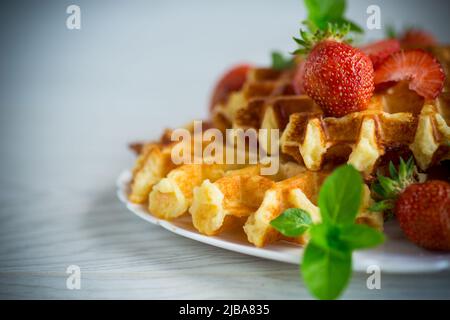 Cialde cagliate dolci con fragole fresche mature, su un tavolo di legno. Foto Stock