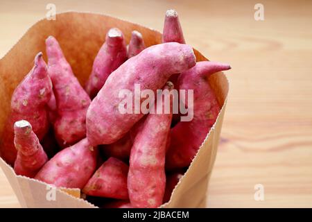 Mucchio di patate dolci viola crude in una borsa di carta Foto Stock