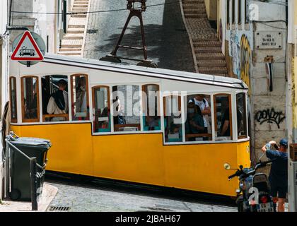 Vista laterale di un tram funicolare Bica e turisti a Lisbona, Portogallo Foto Stock