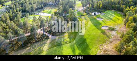 Vista panoramica aerea sul campo da golf nella foresta settentrionale. Le persone non identificate giocano a piedi per cambiare campo da golf, alberi di pino intorno. Caldo giorno di sole eccelle Foto Stock