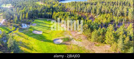 Vista prospettica aerea sul campo da golf nella foresta settentrionale. Persone non identificate giocano a golf sul campo da golf, pinete intorno. Caldo giorno di sole eccellente f Foto Stock