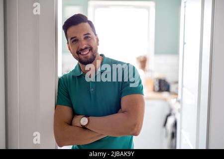 Uomo sorridente in piedi nella porta della cucina Foto Stock