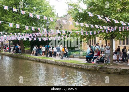 Grande folla sulle rive del fiume Windrush a Bourton godendo soleggiato Platinum Jubilee bank Holiday Foto Stock