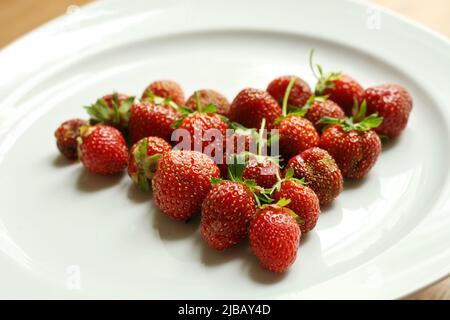 Fragole fresche sul piatto bianco disposte a forma di cuore. San Valentino. Romanticismo. Amore Foto Stock