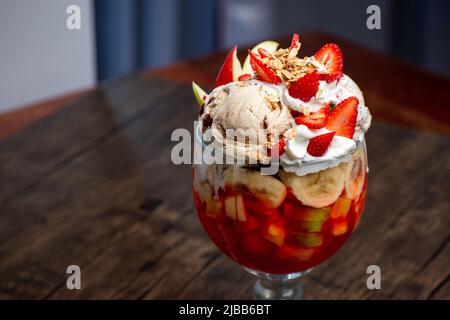 Una tazza di gelato con frutta inclusa fragola e banana Foto Stock