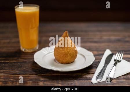 Spuntini brasiliani tradizionali ripieni di pollo; 'Coxinha de Frango' su sfondo di legno Foto Stock