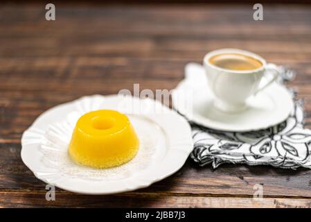 Un dessert brasiliano a base di uova e cocco. Quindim su sfondo in legno Foto Stock
