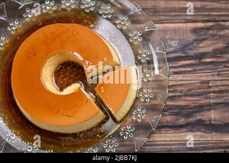 Budino di latte o Pudim de leite. Dessert brasiliano crema di caramello fatta in casa budino. Tradizionale flan brasiliano su sfondo di legno Foto Stock