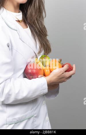 Nutrizionista femminile nel suo ufficio, mostrando verdure e frutta sane. Concetto di salute e dieta. Stile di vita. Foto Stock