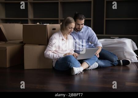 Coppia sposata usa il laptop che acquista su internet il giorno del trasferimento Foto Stock
