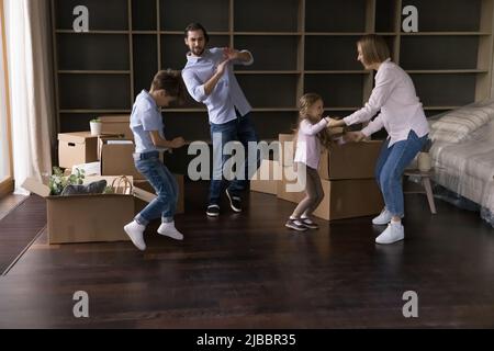 La famiglia con i bambini balla in soggiorno il giorno della delocalizzazione Foto Stock