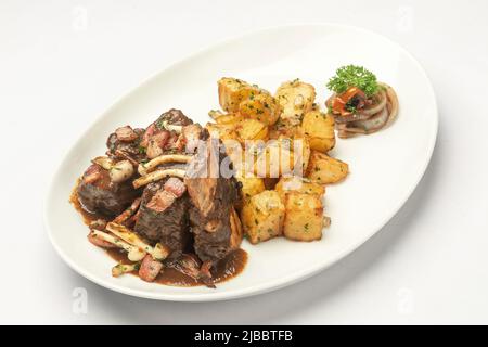 costolette di manzo stufato e funghi in salsa con patate arrosto su sfondo bianco Foto Stock