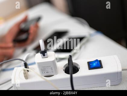 Berlino, Germania. 04th giugno 2022. Numerosi cavi e caricabatterie sono collegati a una basetta di alimentazione mentre tre smartphone si stanno caricando in background. Credit: Monika Skolimowska/dpa/Alamy Live News Foto Stock