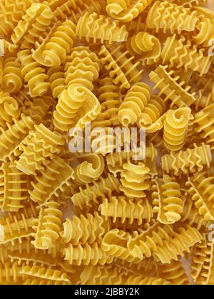 Primi piatti ricci asciutti. Pasta fatta di grano duro vista dall'alto. Fondo macaroni non bollito giallo. Foto Stock