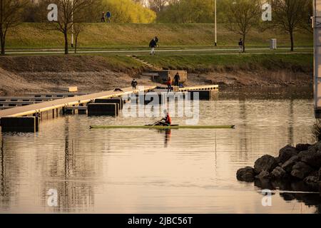 Zagabria, Croazia-1st aprile 2022: Uomo in kayak canottaggio al lago jarun, Croazia con nuovi moli in costruzione di recente sulla riva Foto Stock