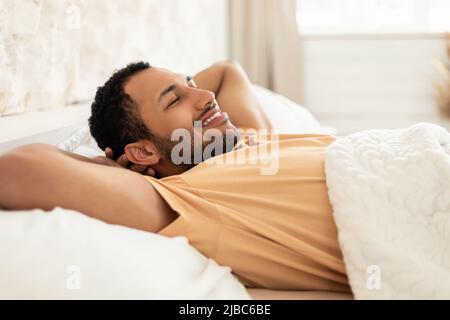 Uomo Arabo rilassante sdraiato con gli occhi chiusi nella moderna camera da letto Foto Stock