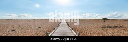 Il promontorio di Dungeness è una spiaggia di ciottoli, simile a un deserto, spazzata dal vento. Questo sentiero in legno conduce attraverso le pietre al canale Inglese. Foto Stock