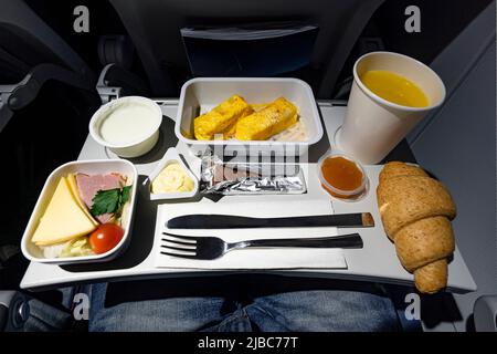 Una varietà di cibo sul tavolo pieghevole sull'aereo. Cena in tarda serata durante il volo. Foto Stock