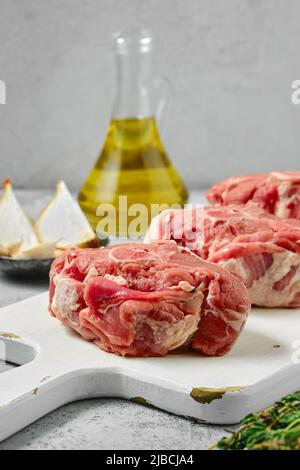 Il lombo di agnello crudo non cotti le bistecche della sella sul tagliere di legno, vista dal primo piano Foto Stock