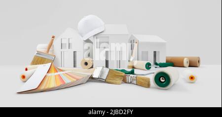 casa pittore strumenti, spazzole, rulli di vernice, carta mascheratura nastro e colori campioni su scrivania con modello casa, fornitura e servizio in negozio di colore in Foto Stock