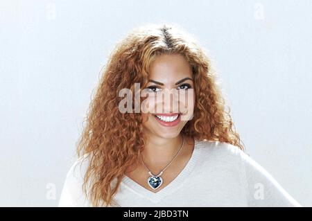 Giovane donna sorridente, con capelli ricci rossi e pendente in cristallo blu. Foto Stock