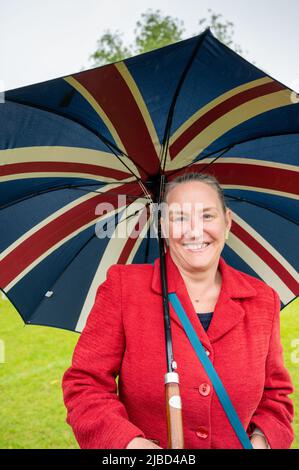 Willingham Cambridgeshire, Regno Unito. 5th giugno 2022. La gente festeggia il fine settimana del Giubileo del platino della Regina sotto la pioggia in un picnic sul terreno ricreativo. Molta gente era determinata a celebrare l'occasione nonostante la pioggia gocciolante, portando i propri picnic e godendo di una band blues, bancarelle di cibo, bar e giochi. Credit: Julian Eales/Alamy Live News Foto Stock
