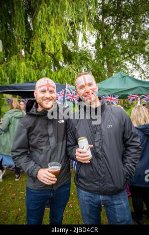 Willingham Cambridgeshire, Regno Unito. 5th giugno 2022. La gente festeggia il fine settimana del Giubileo del platino della Regina sotto la pioggia in un picnic sul terreno ricreativo. Molta gente era determinata a celebrare l'occasione nonostante la pioggia gocciolante, portando i propri picnic e godendo di una band blues, bancarelle di cibo, bar e giochi. Credit: Julian Eales/Alamy Live News Foto Stock