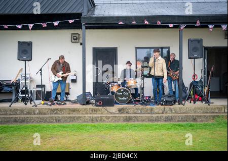 Willingham Cambridgeshire, Regno Unito. 5th giugno 2022. La gente festeggia il fine settimana del Giubileo del platino della Regina sotto la pioggia in un picnic sul terreno ricreativo. Molta gente era determinata a celebrare l'occasione nonostante la pioggia gocciolante, portando i propri picnic e godendo di una band blues, bancarelle di cibo, bar e giochi. Credit: Julian Eales/Alamy Live News Foto Stock