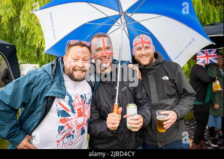 Willingham Cambridgeshire, Regno Unito. 5th giugno 2022. La gente festeggia il fine settimana del Giubileo del platino della Regina sotto la pioggia in un picnic sul terreno ricreativo. Molta gente era determinata a celebrare l'occasione nonostante la pioggia gocciolante, portando i propri picnic e godendo di una band blues, bancarelle di cibo, bar e giochi. Credit: Julian Eales/Alamy Live News Foto Stock