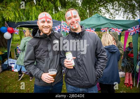 Willingham Cambridgeshire, Regno Unito. 5th giugno 2022. La gente festeggia il fine settimana del Giubileo del platino della Regina sotto la pioggia in un picnic sul terreno ricreativo. Molta gente era determinata a celebrare l'occasione nonostante la pioggia gocciolante, portando i propri picnic e godendo di una band blues, bancarelle di cibo, bar e giochi. Credit: Julian Eales/Alamy Live News Foto Stock