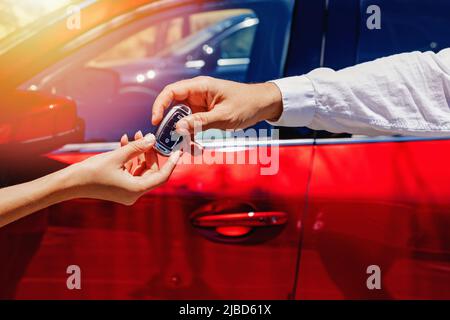 Gli uomini che prendono le chiavi dall'automobile dalla mano del venditore o del lavoratore di noleggio dell'automobile. Acquistare o noleggiare un'auto Foto Stock