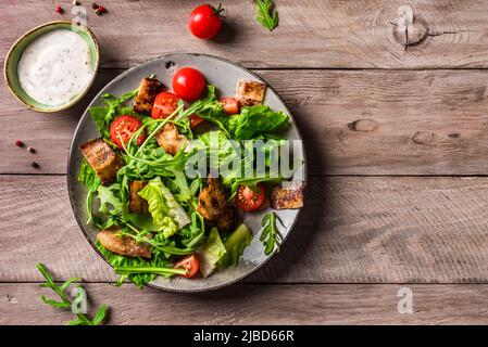 Insalata BLT con pancetta, lattuga, pomodori su tavola di legno, vista dall'alto, spazio copia. Insalata classica americana con pancetta per un pranzo sano. Foto Stock