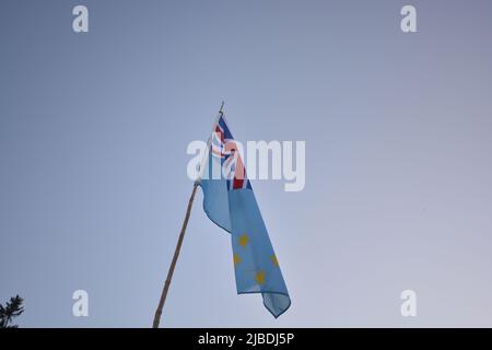Bandiera nazionale Tuvalu che sventola nel vento su un cielo blu profondo. Tessuto di alta qualità. Concetto di relazioni internazionali. Foto Stock