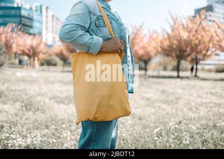 La donna tiene in mano il tessuto di tela della borsa della borsa per il modello bianco del mockup. Foto Stock