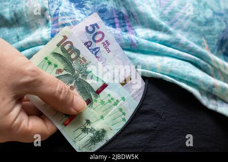 La donna prende denaro colombiano, centocinquanta banconote di pesos dalla sua tasca Foto Stock