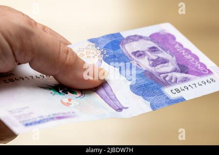 Mano femminile che detiene una banconota da 50 pesos in Colombia Foto Stock