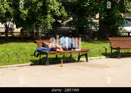 Giovane uomo che dorme su panchina nel parco pubblico in una giornata di sole a Sofia, Bulgaria, Europa dell'Est, Balcani, UE Foto Stock
