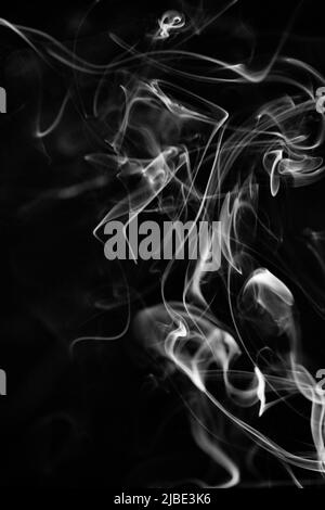 Un modello di fumo bianco, vorticoso, ascendente su uno sfondo nero, la foto potrebbe essere usata come sfondo, trama di fumo o astratto, o pho di stock generale Foto Stock