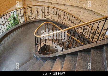 scala a chiocciola all'interno con pavimento in marmo ed eleganti balaustre in ferro battuto con ringhiere in legno Foto Stock