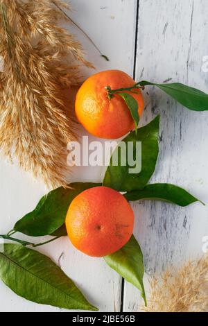 agrumi d'arancia su tavola bianca con foglie verdi Foto Stock